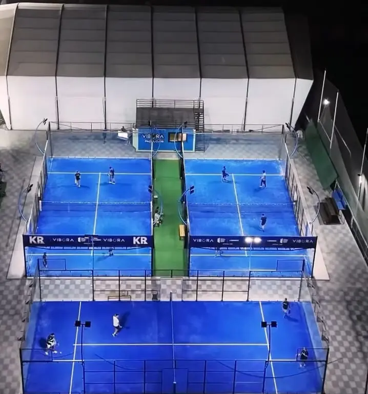 An empty professional outdoor padel court under a clear blue sky.