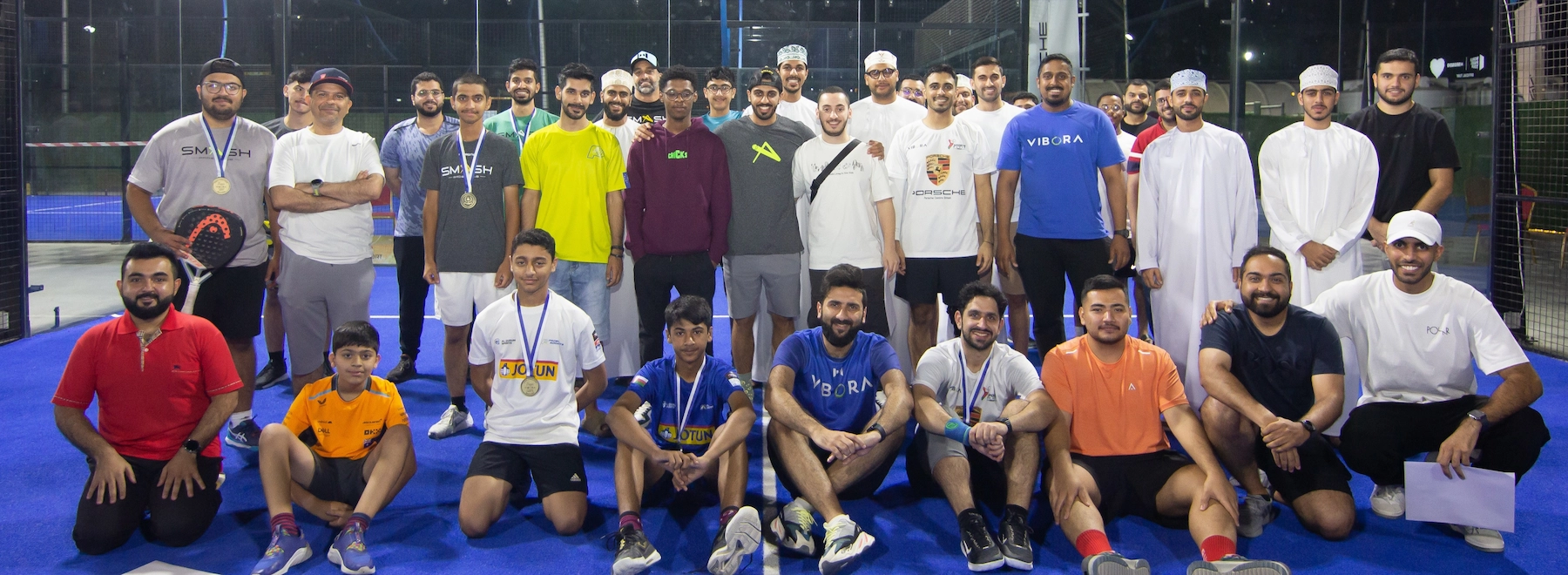 A diverse team of sports coaches and players posing together happily at the club